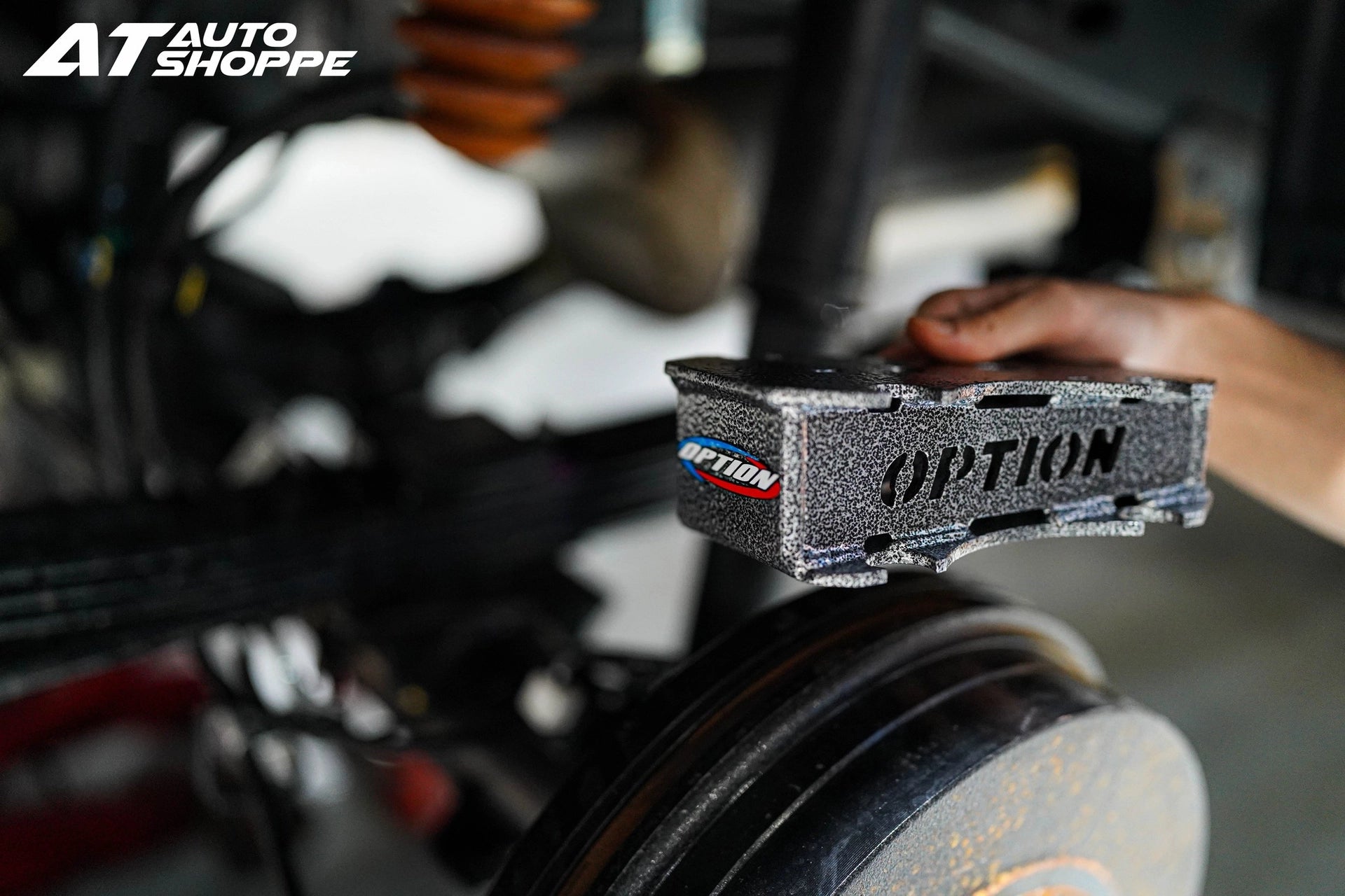 Car part with 'OPTION' branding on a blurred background of an auto shop.