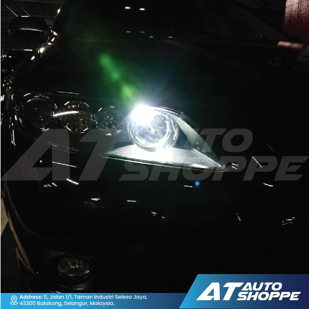 Car headlight with a bright light on a dark background, featuring AT Auto Shoppe branding.