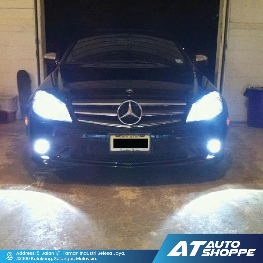 Mercedes-Benz car with illuminated headlights in a garage, featuring AT Auto Shoppe branding.