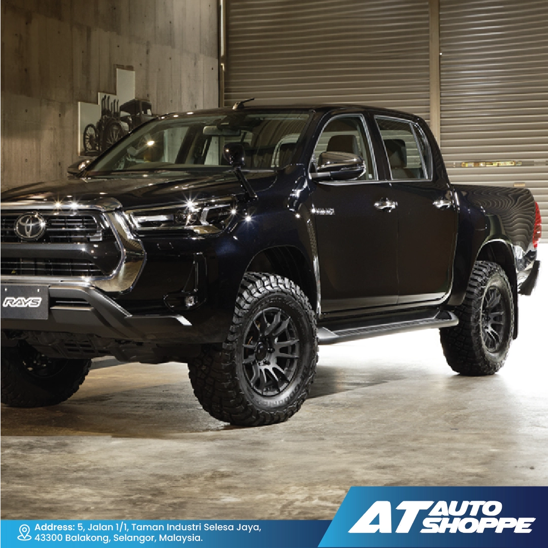 Black Toyota pickup truck in a warehouse setting with 'AT Auto Shoppe' branding.