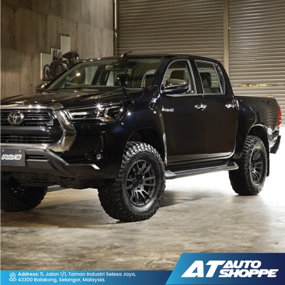 Black Toyota pickup truck in a warehouse setting with 'AT Auto Shoppe' branding.