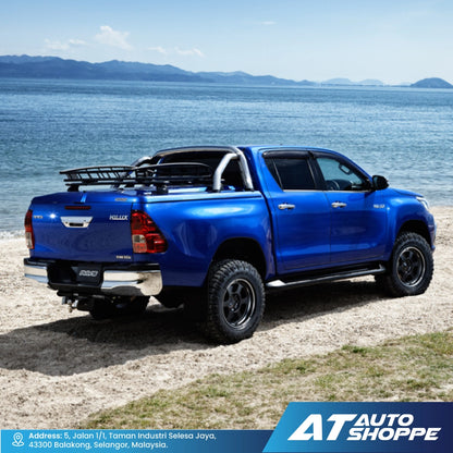Blue pickup truck on a beach with ocean and mountains in the background, featuring AT Auto Shoppe branding.