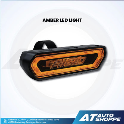 Rigid Industries Amber LED light with 'AT Auto Shoppe' branding on a white background