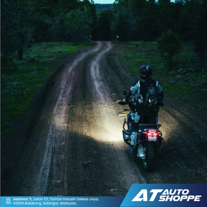 Person riding a motorcycle on a dark forest road with 'AT Auto Shoppe' branding.