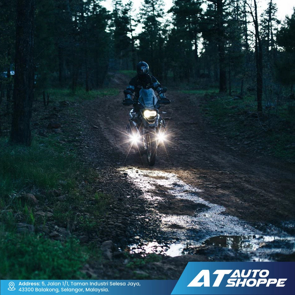 Motorcycle with headlights on a muddy forest trail at night, with 'AT Auto Shoppe' branding.