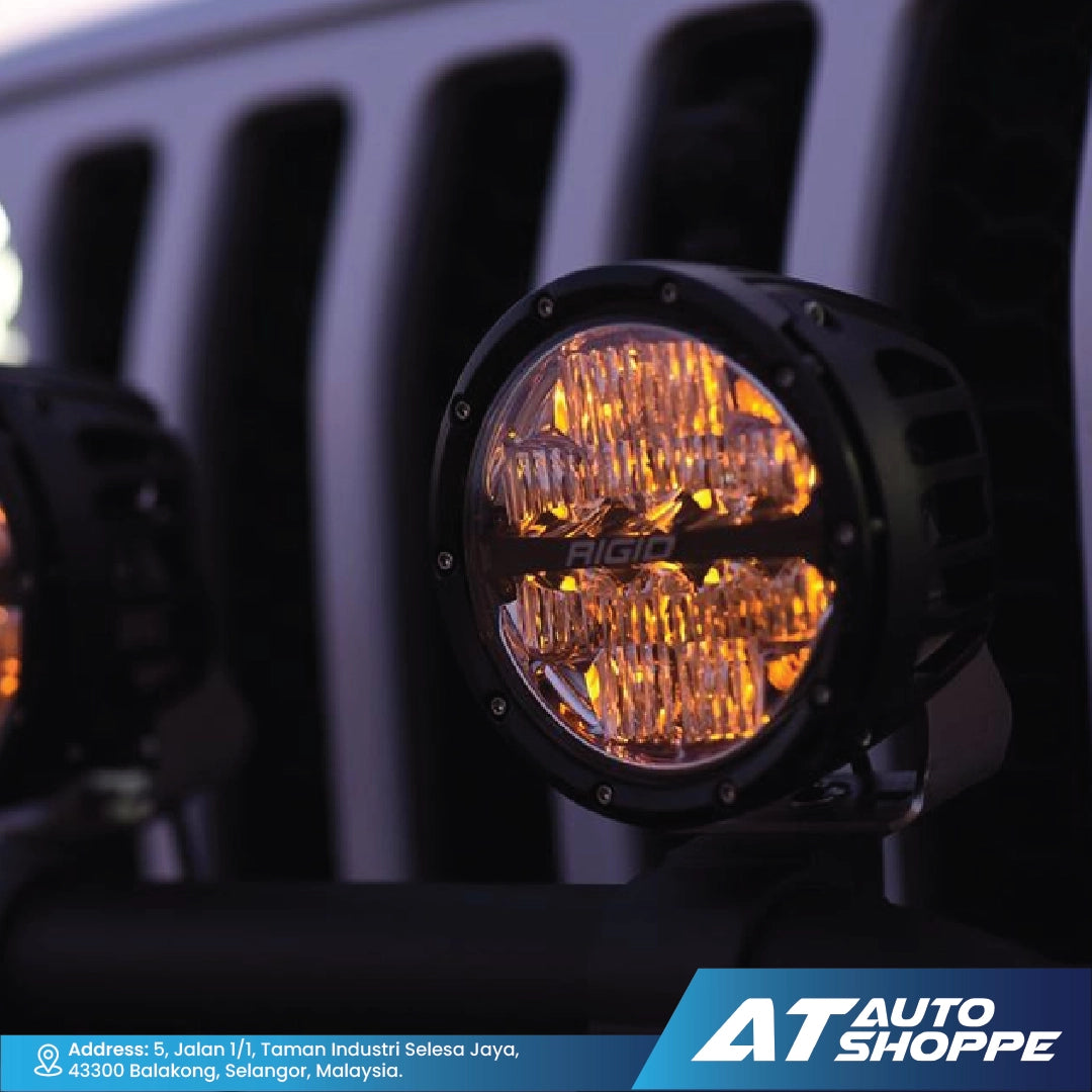 Close-up of a Rigid Industries LED light on a vehicle with 'AT Auto Shoppe' branding.