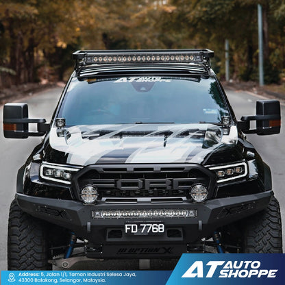 Ford truck with additional lights on a road, featuring AT Auto Shoppe branding.