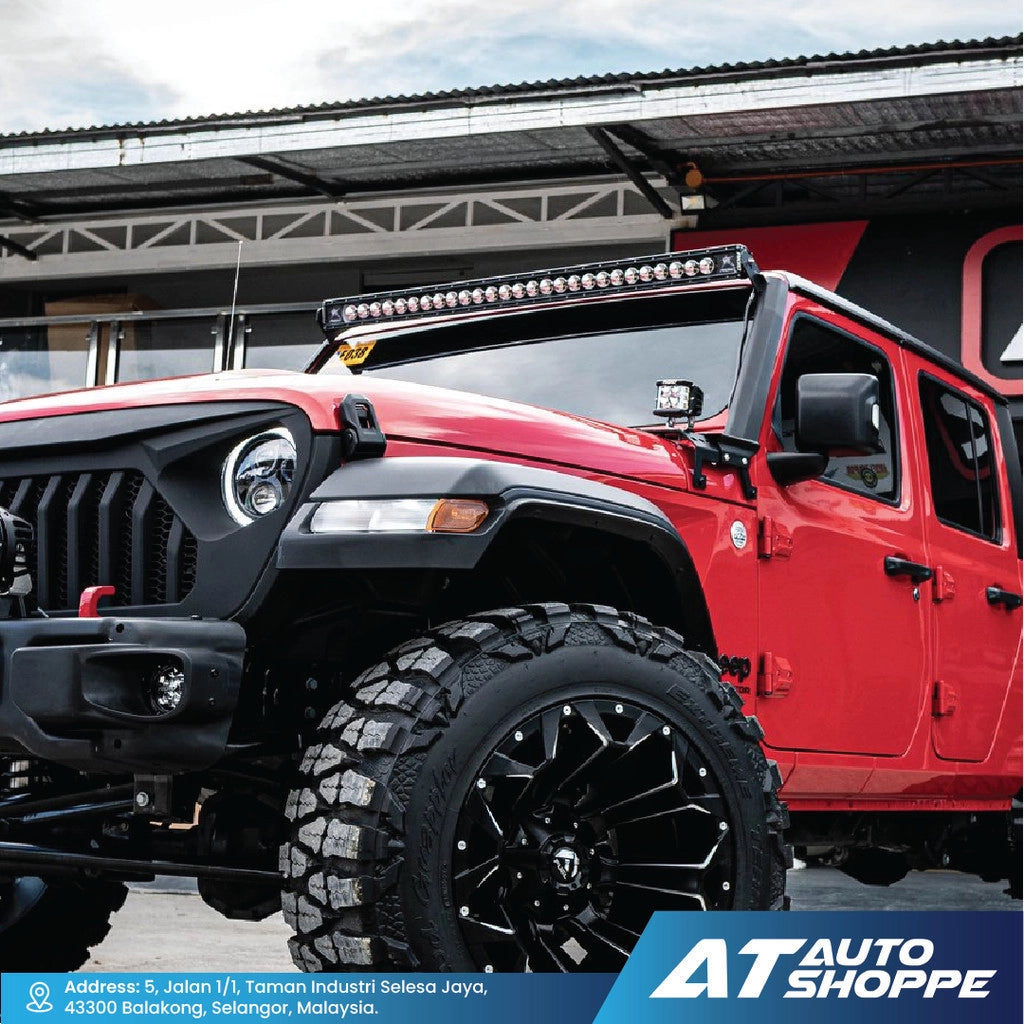 Red Jeep Wrangler with off-road equipment on a paved surface, featuring AT Auto Shoppe branding.