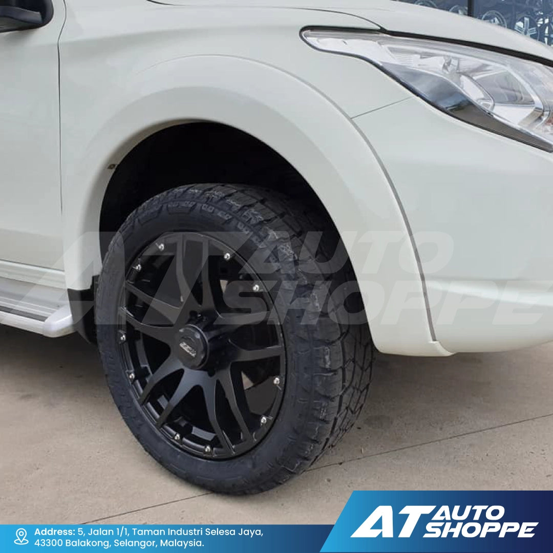 Close-up of a car wheel with black rim and tire on a white vehicle, branded with AT Auto Shoppe.