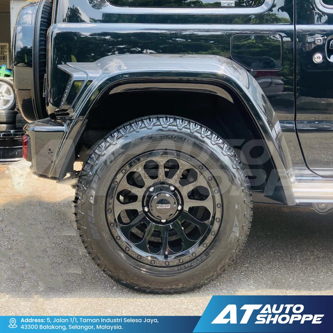 Close-up of a black off-road vehicle tire with a visible brand logo on a concrete surface.