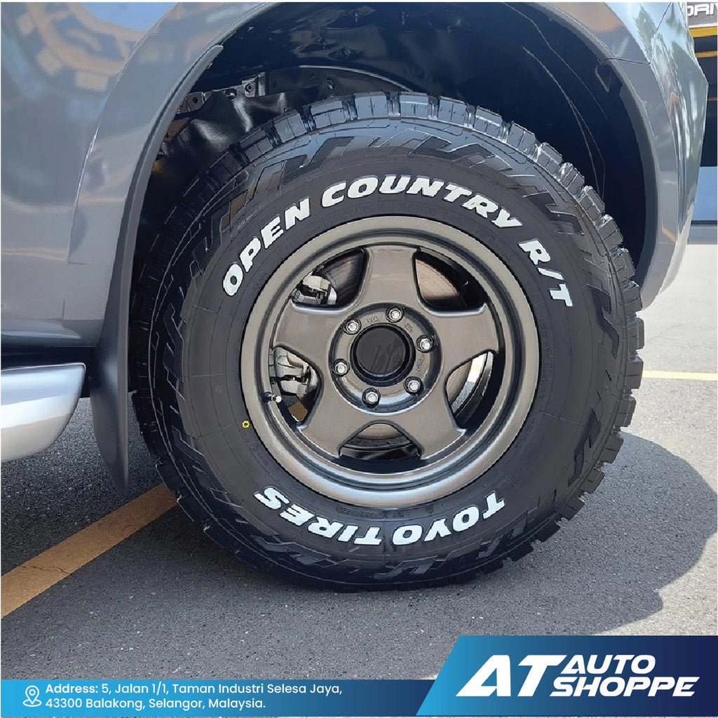 Close-up of a Toyo Open Country RT tire on a vehicle in a parking lot with AT Auto Shoppe branding.