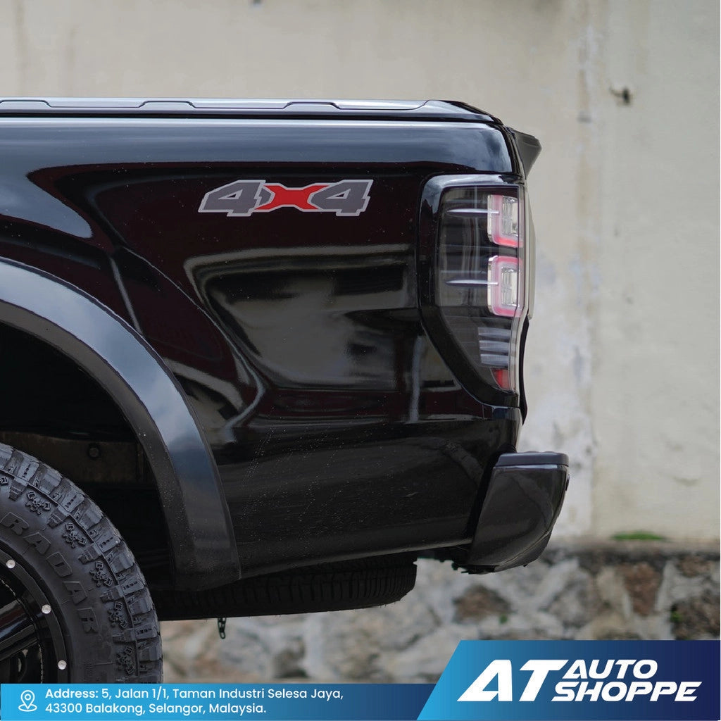 Close-up of a black vehicle's 4x4 badge with a blurred background and AT Auto Shoppe branding.