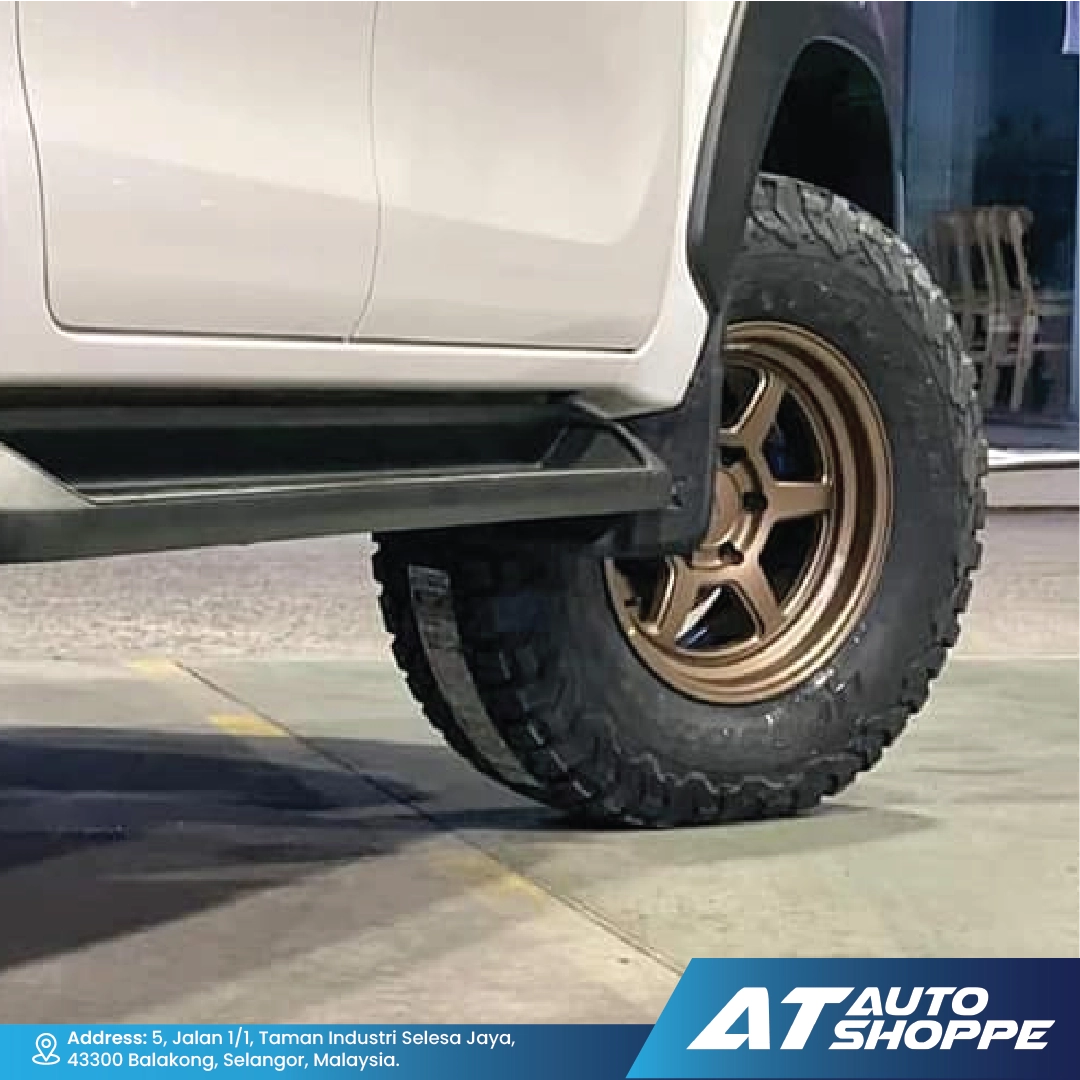 Close-up of a vehicle tire with a bronze VLF rim on a concrete surface, featuring the AT Auto Shoppe logo.
