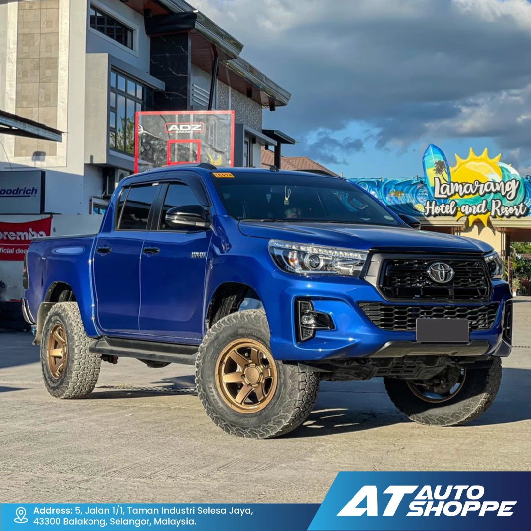 Blue Toyota pickup truck with VLF bronze wheels on a street, featuring AT Auto Shoppe branding.