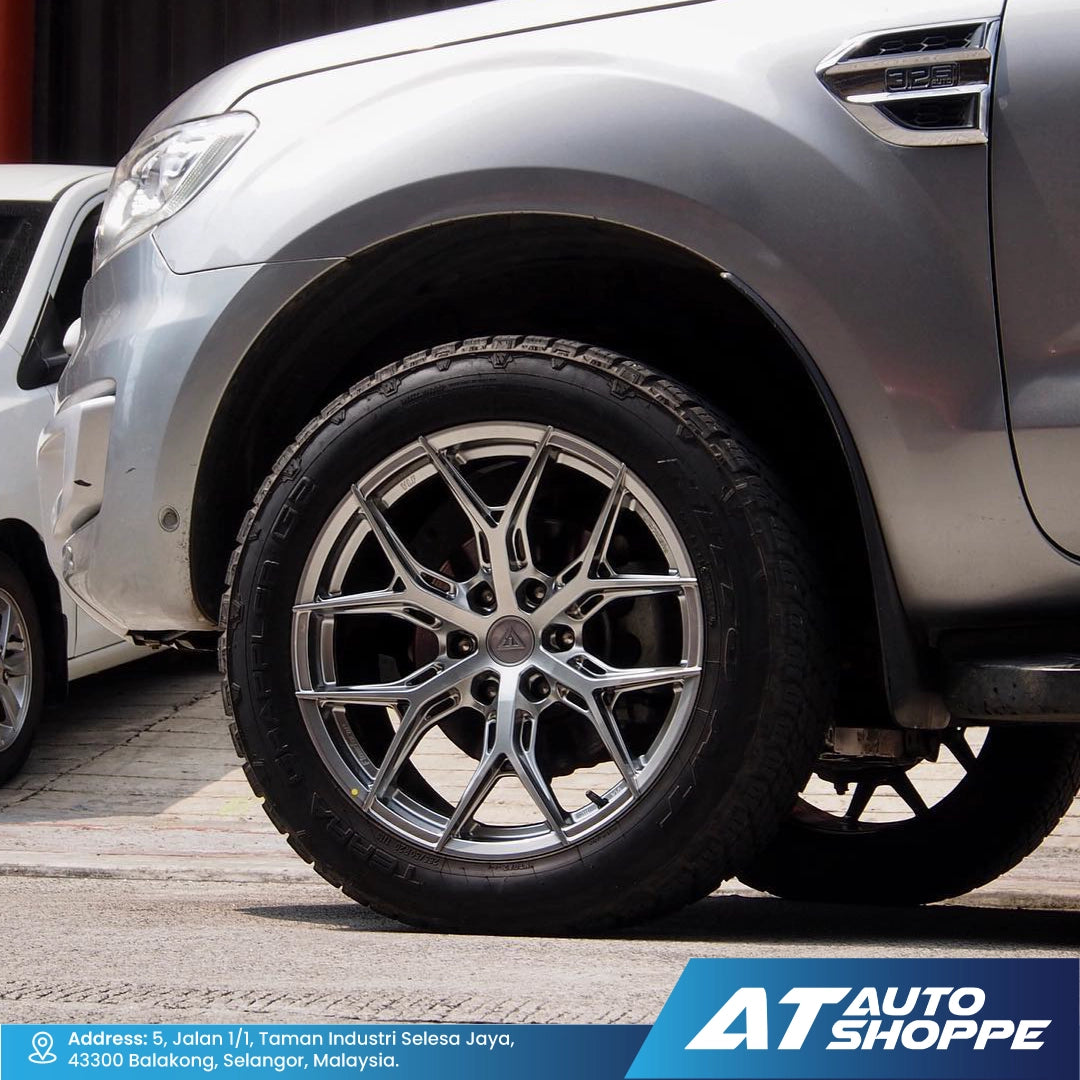 Close-up of a car wheel with VLF rim, parked on a street, with AT Auto Shoppe branding.