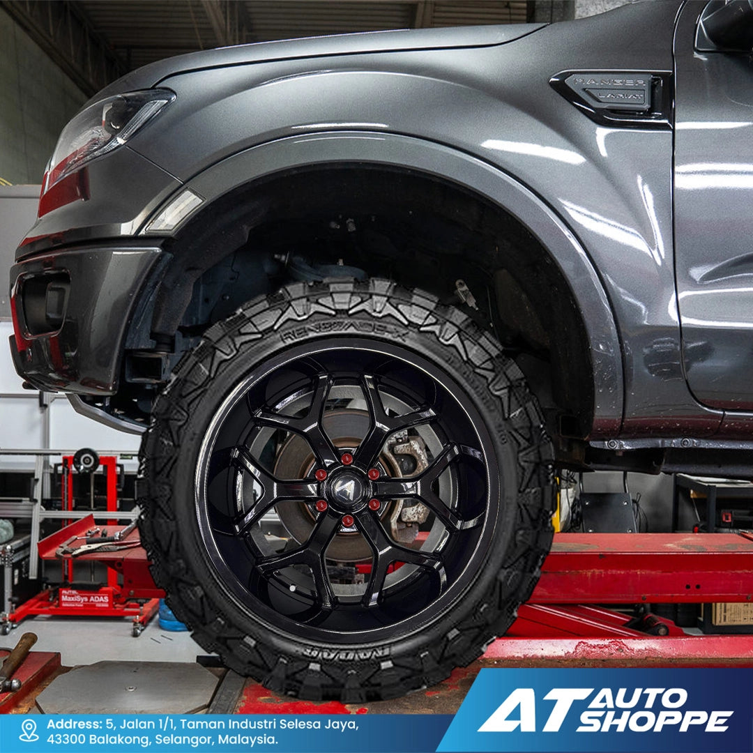 Gray truck with a black tire and Vampire  rim on a lift at AT Auto Shoppe.