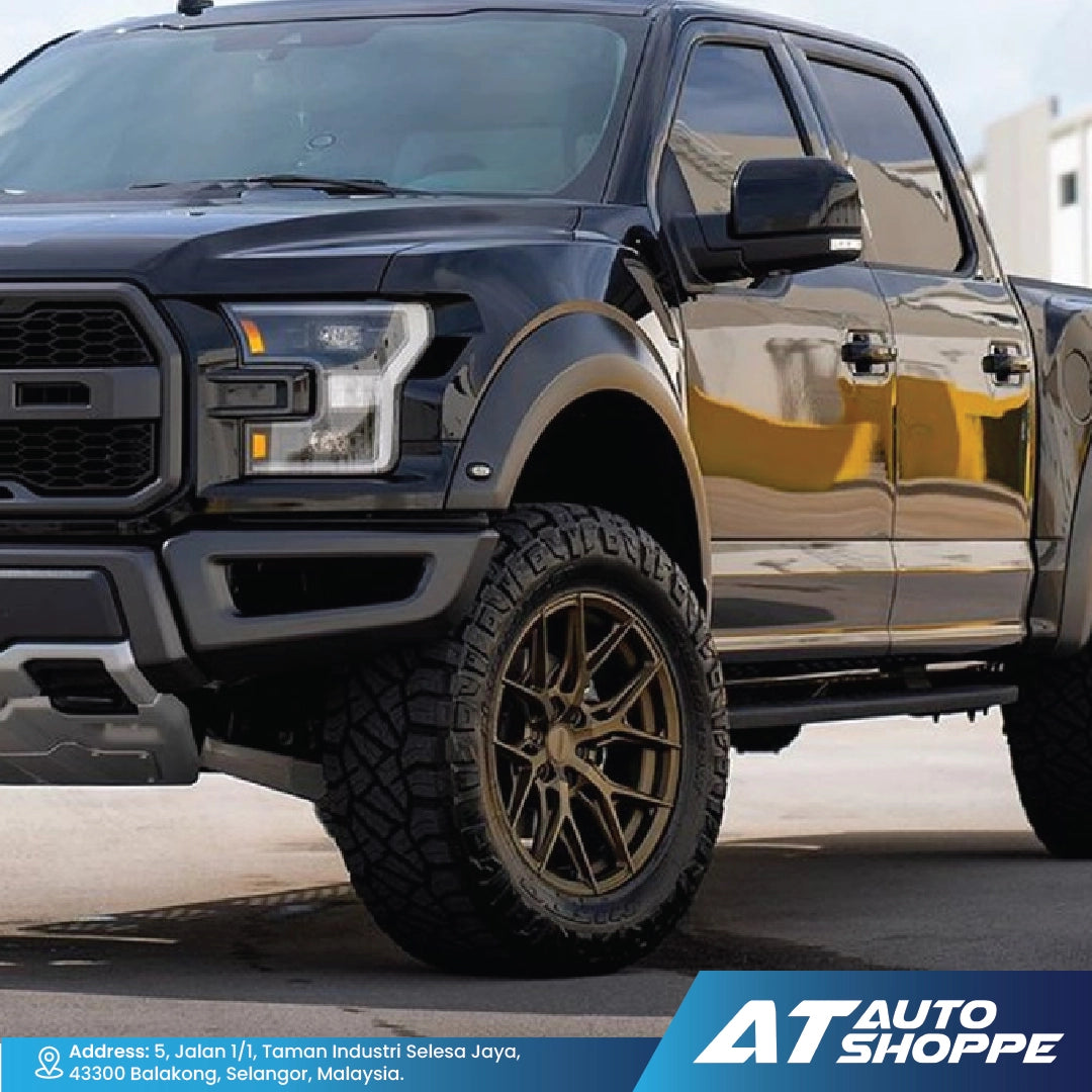 Black pickup truck with gold rims on a road, featuring AT Auto Shoppe branding.