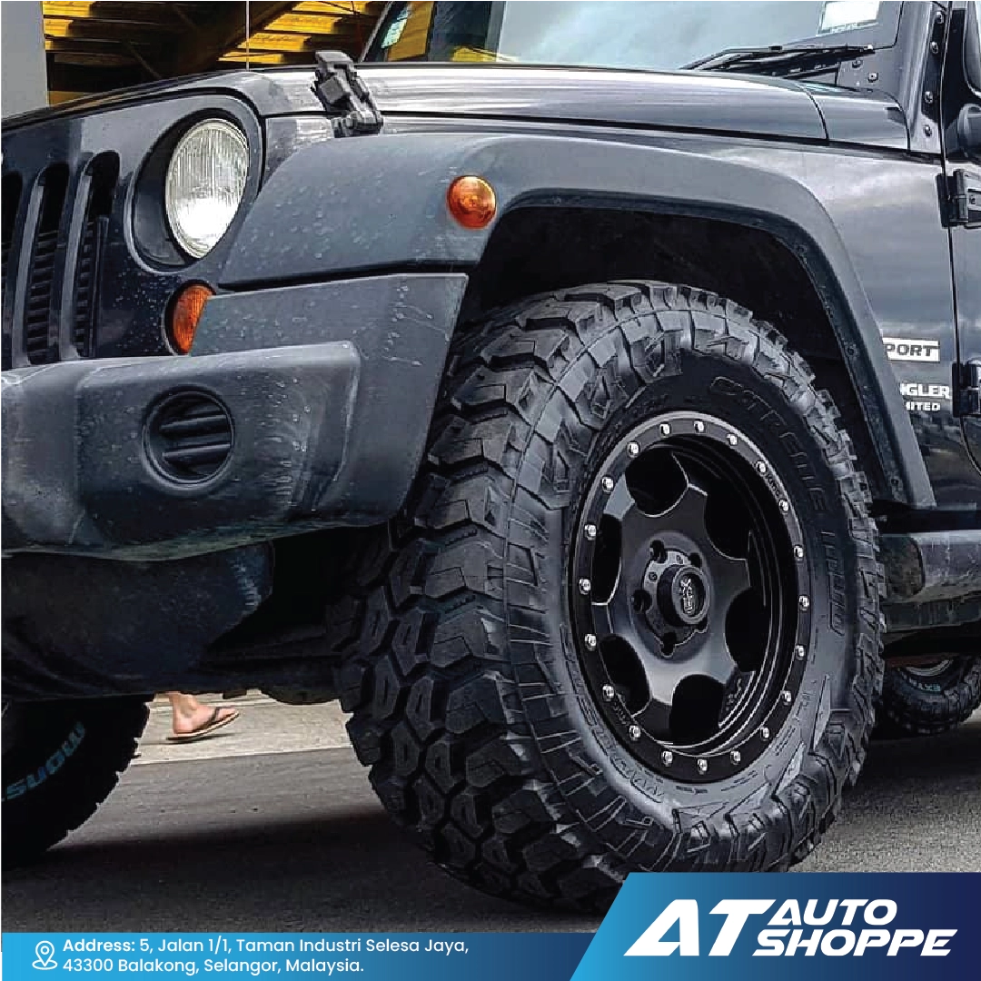 Black off-road vehicle with large tires and 'AT Auto Shoppe' branding.
