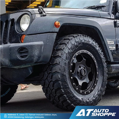 Black off-road vehicle with large tires and 'AT Auto Shoppe' branding.
