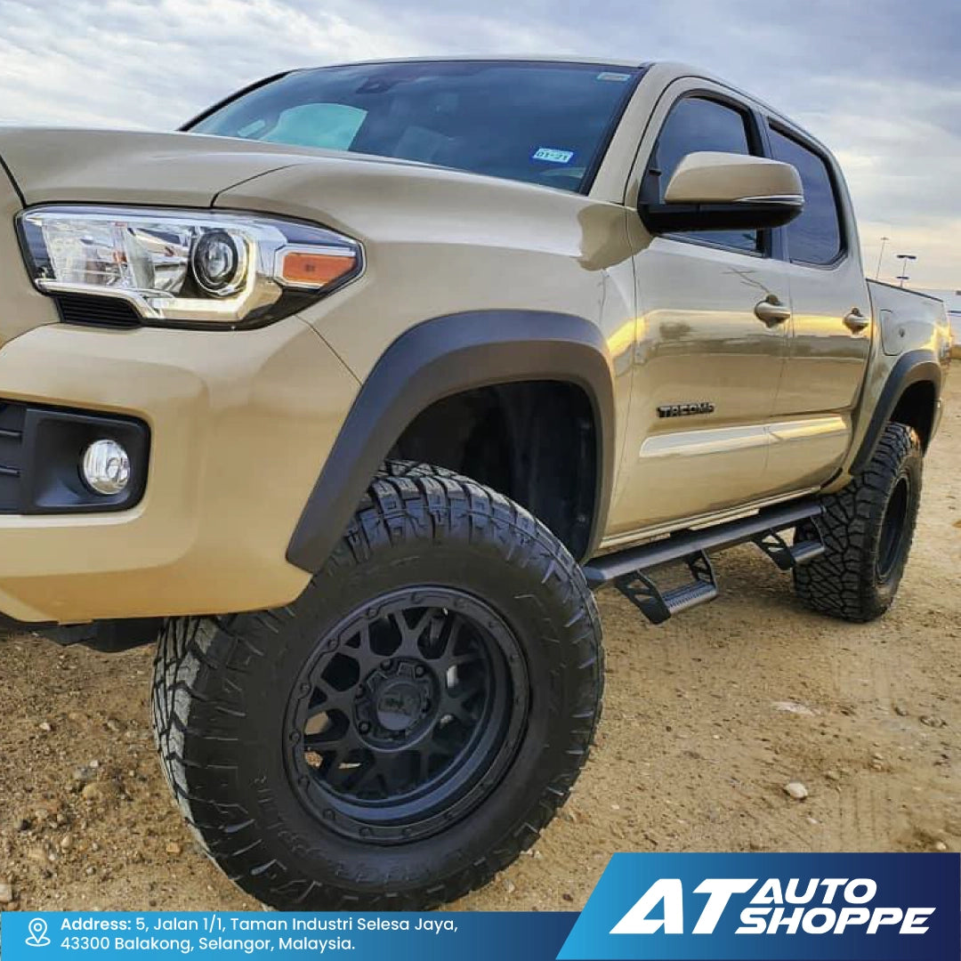 Beige pickup truck on a dirt road with 'AT Auto Shoppe' branding.