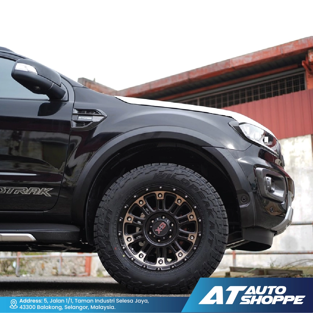 Black SUV with large off-road tires and AT Auto Shoppe branding.