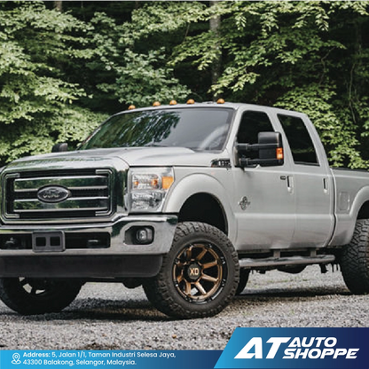 Silver Ford truck parked on a gravel road with trees in the background, featuring AT Auto Shoppe branding.
